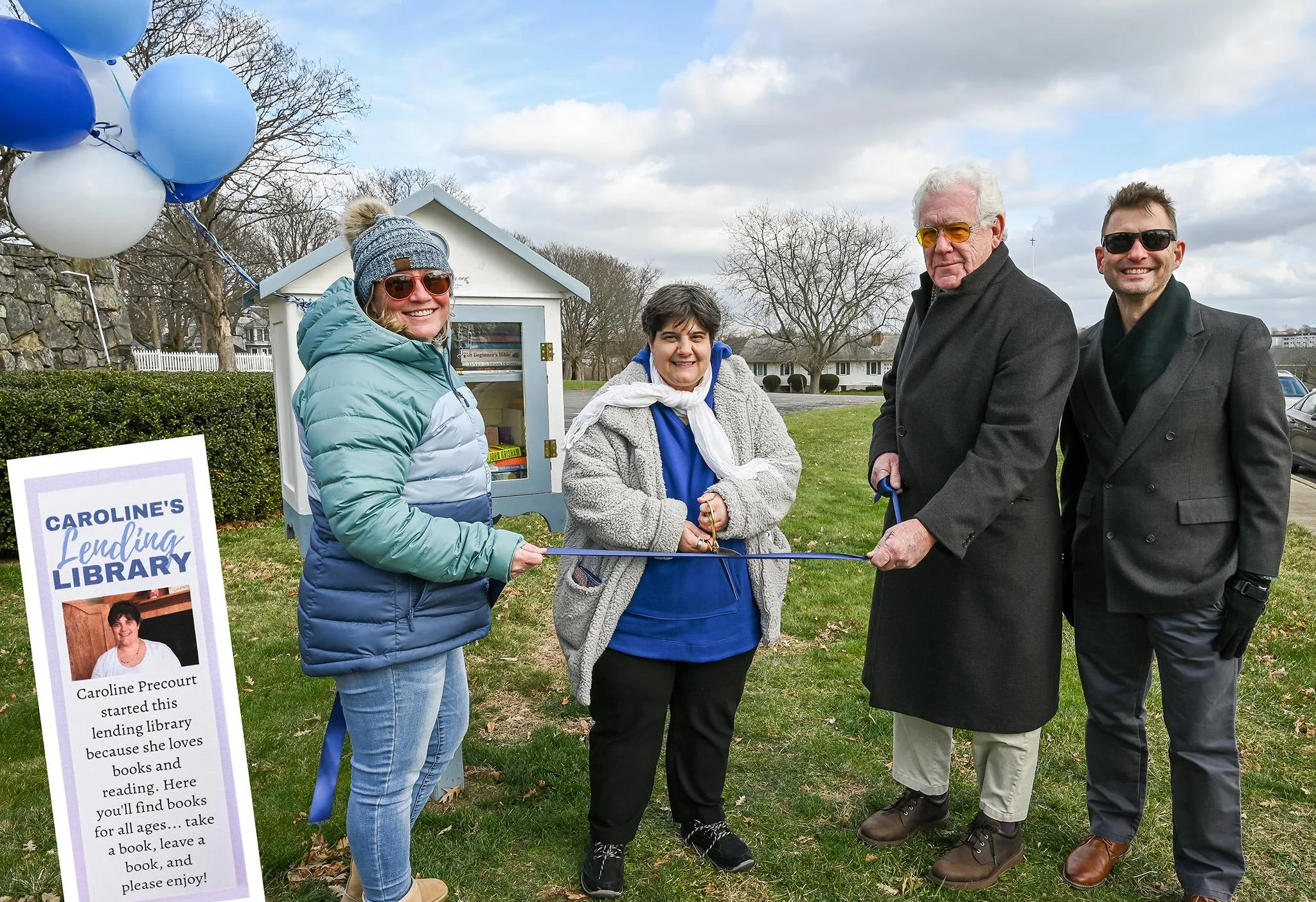 Community members join young woman in ribbon cutting for her little free library