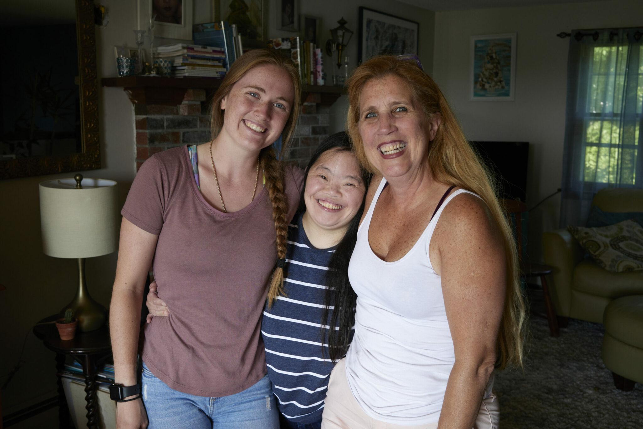 3 smiling women pose for picture in their home