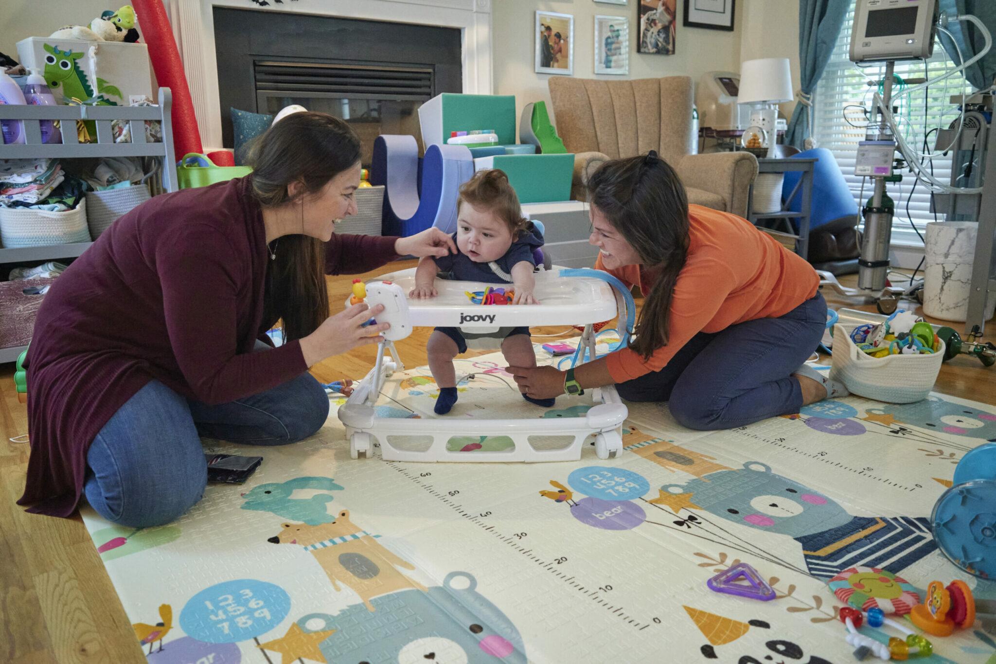 Mother and physical therapist helping toddler learn to walk