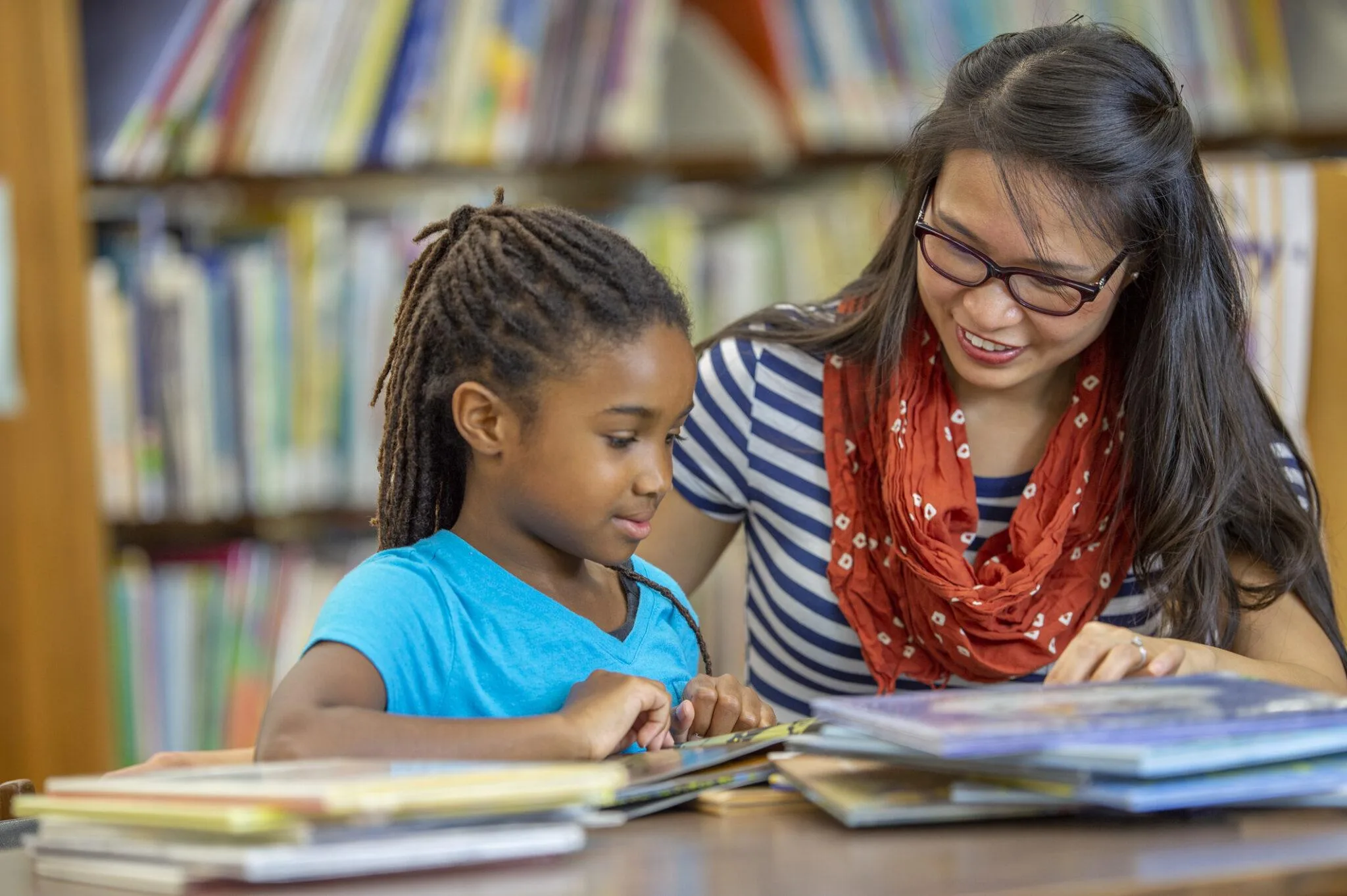 Woman supporting grade school student to read