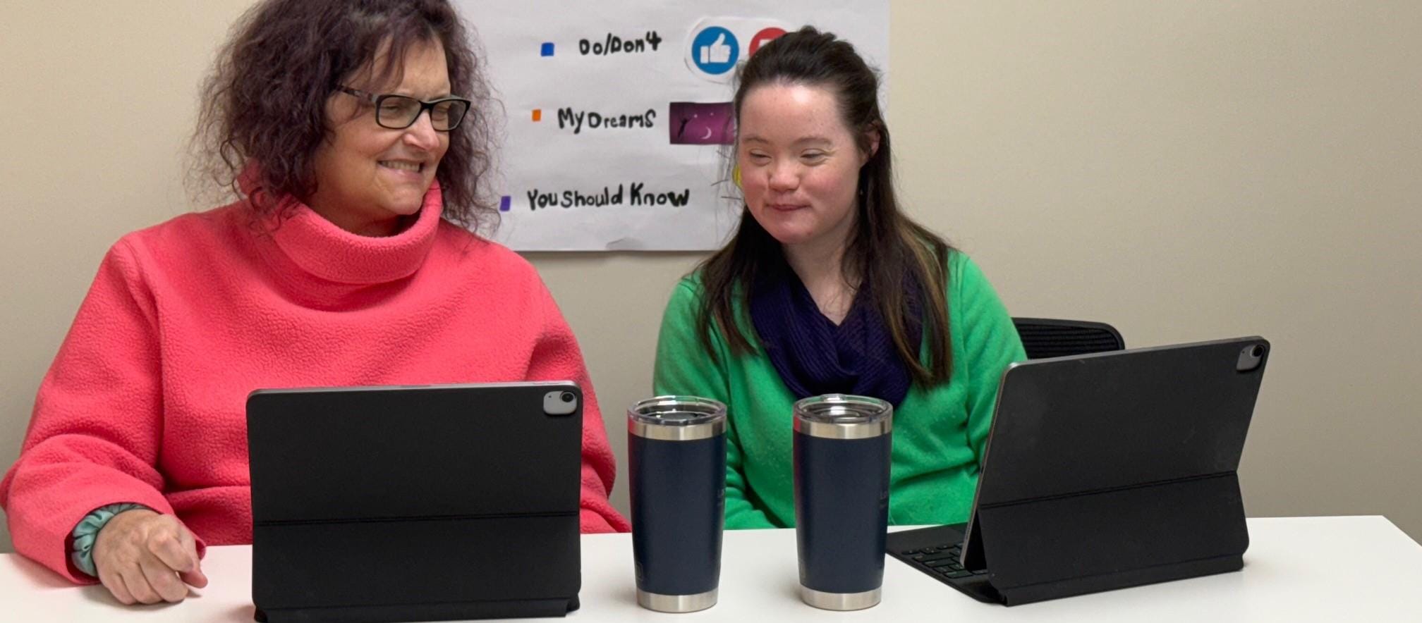 An_individual_and_a_person-driven_services_staff_member_sit together_with_computers_working_on_a_self_advocacy_video Person-Driven Services for adults with disabilities in RI