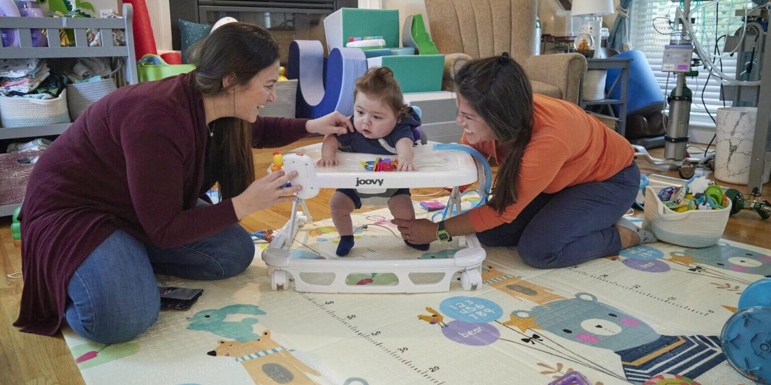 Mother and physical therapist helping toddler learn to walk