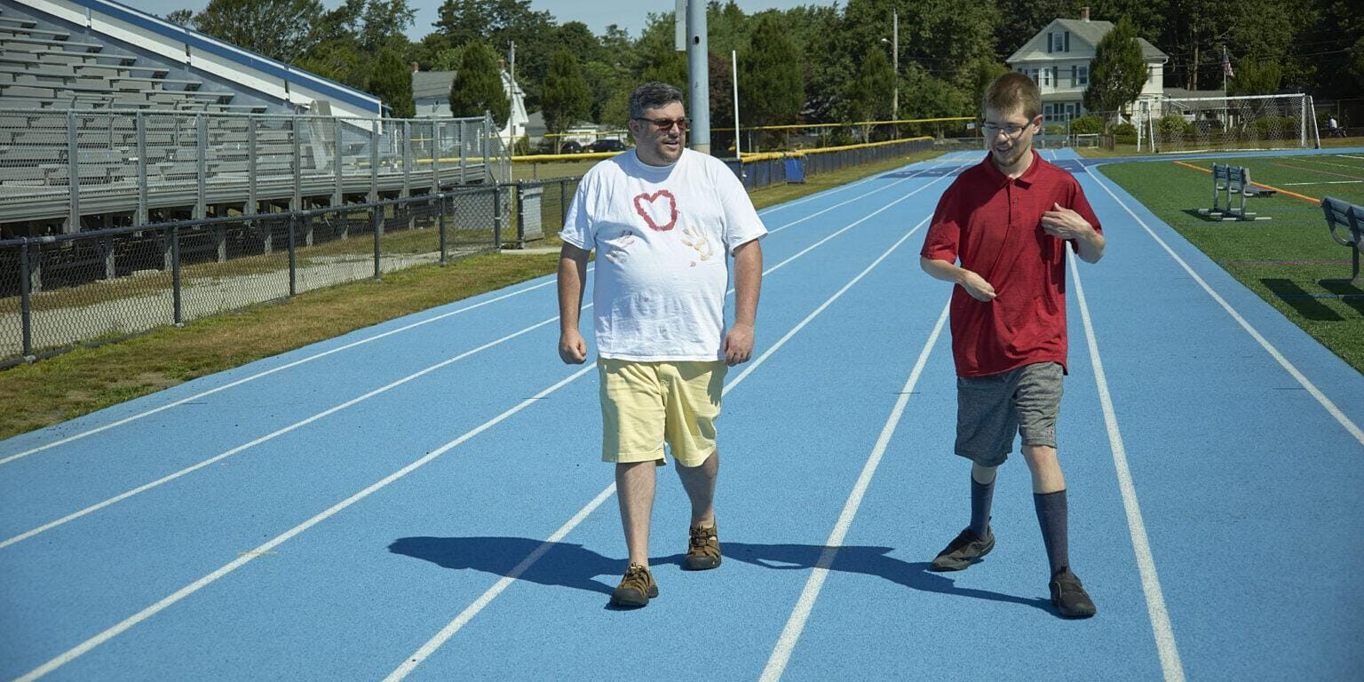 Two men talking and walking on track