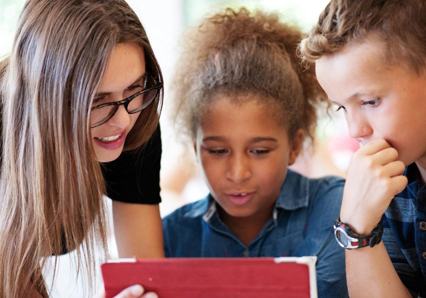 Services for Schools Link - Photo shows young woman assisting two students on tablet